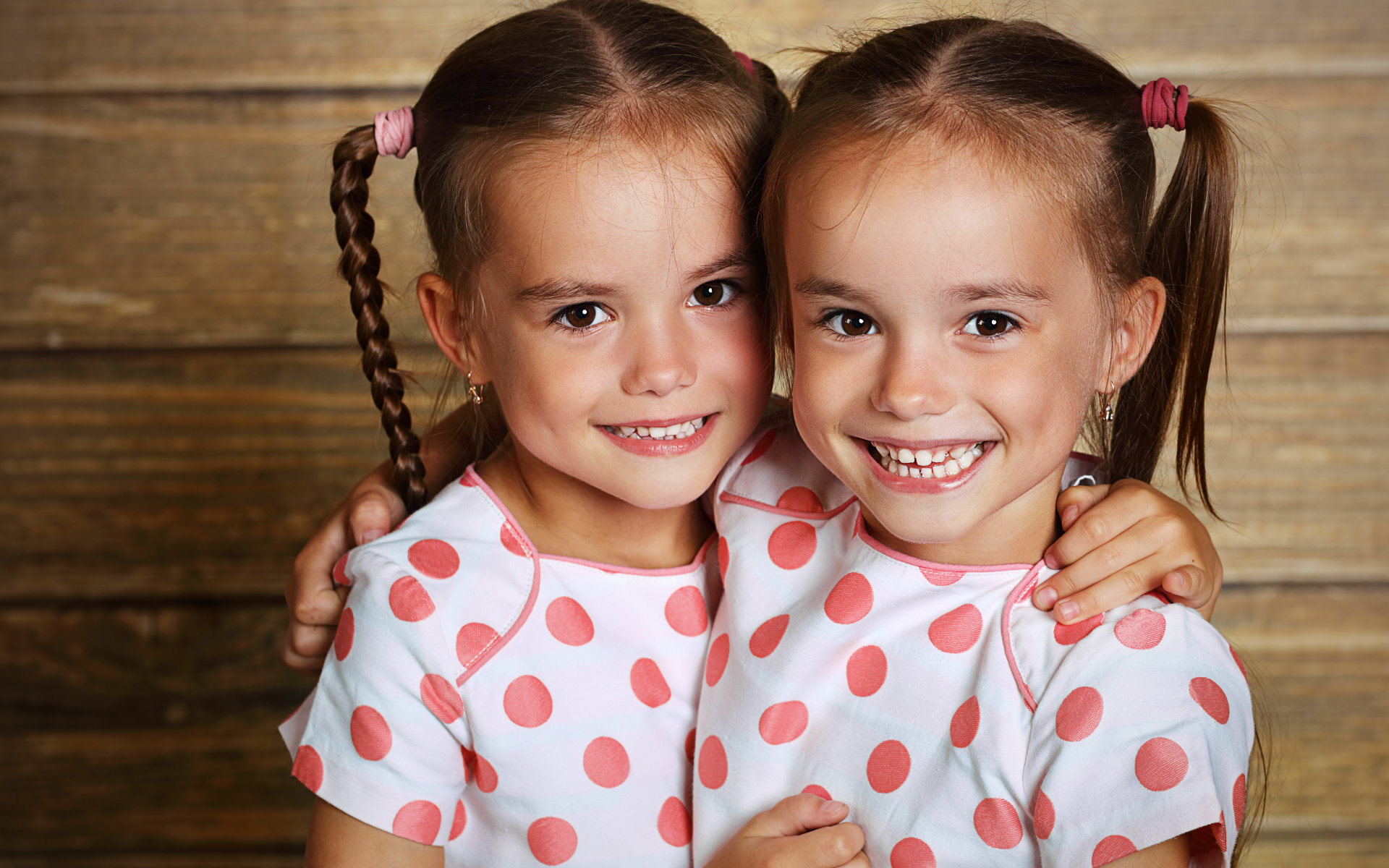 Little twin sisters showing nice teeth in their smiles.