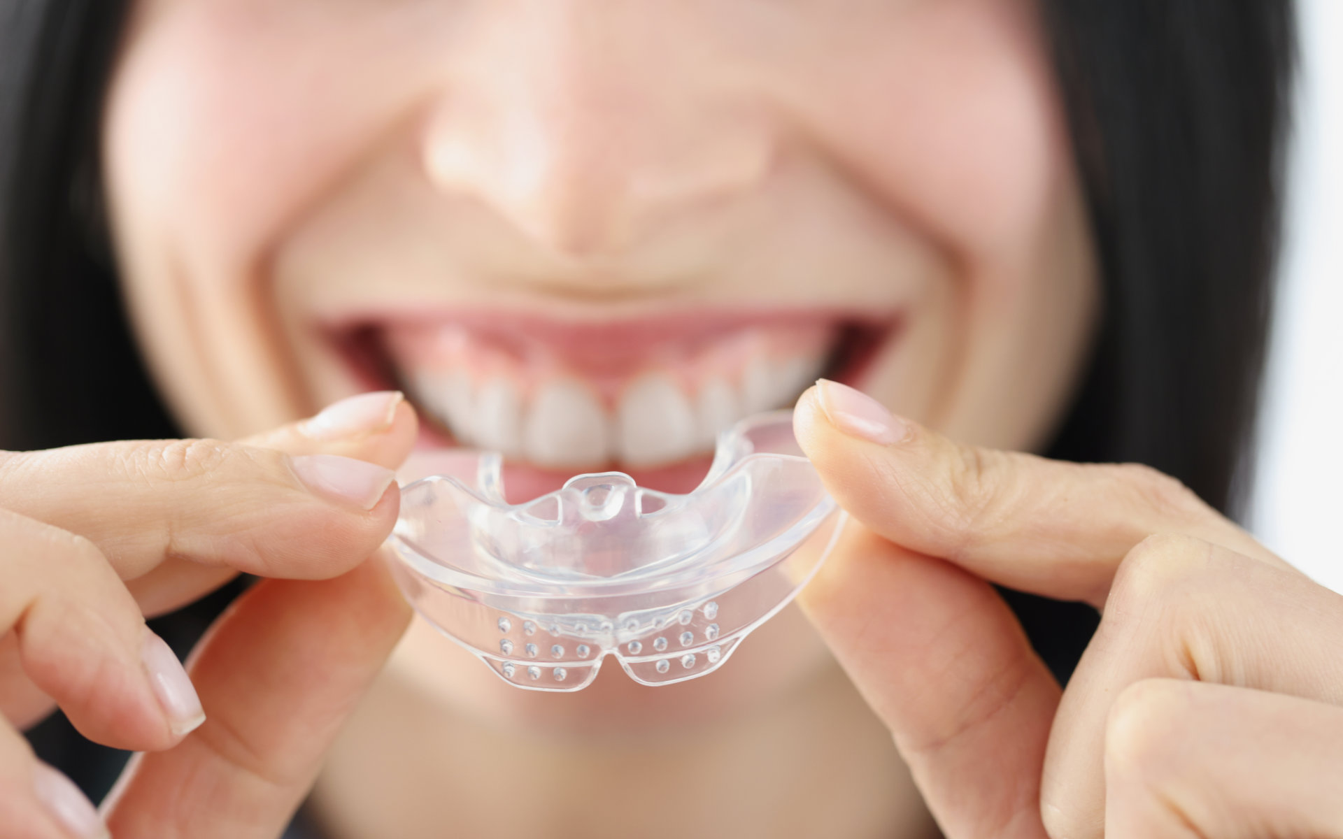 A happy woman holding a dental night guardaligner.