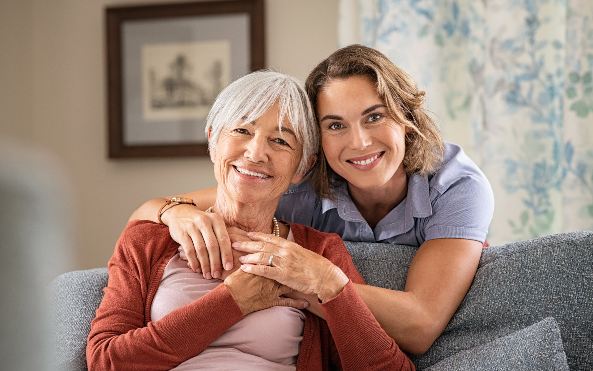 A broadly smiling mature woman embracing her mother.