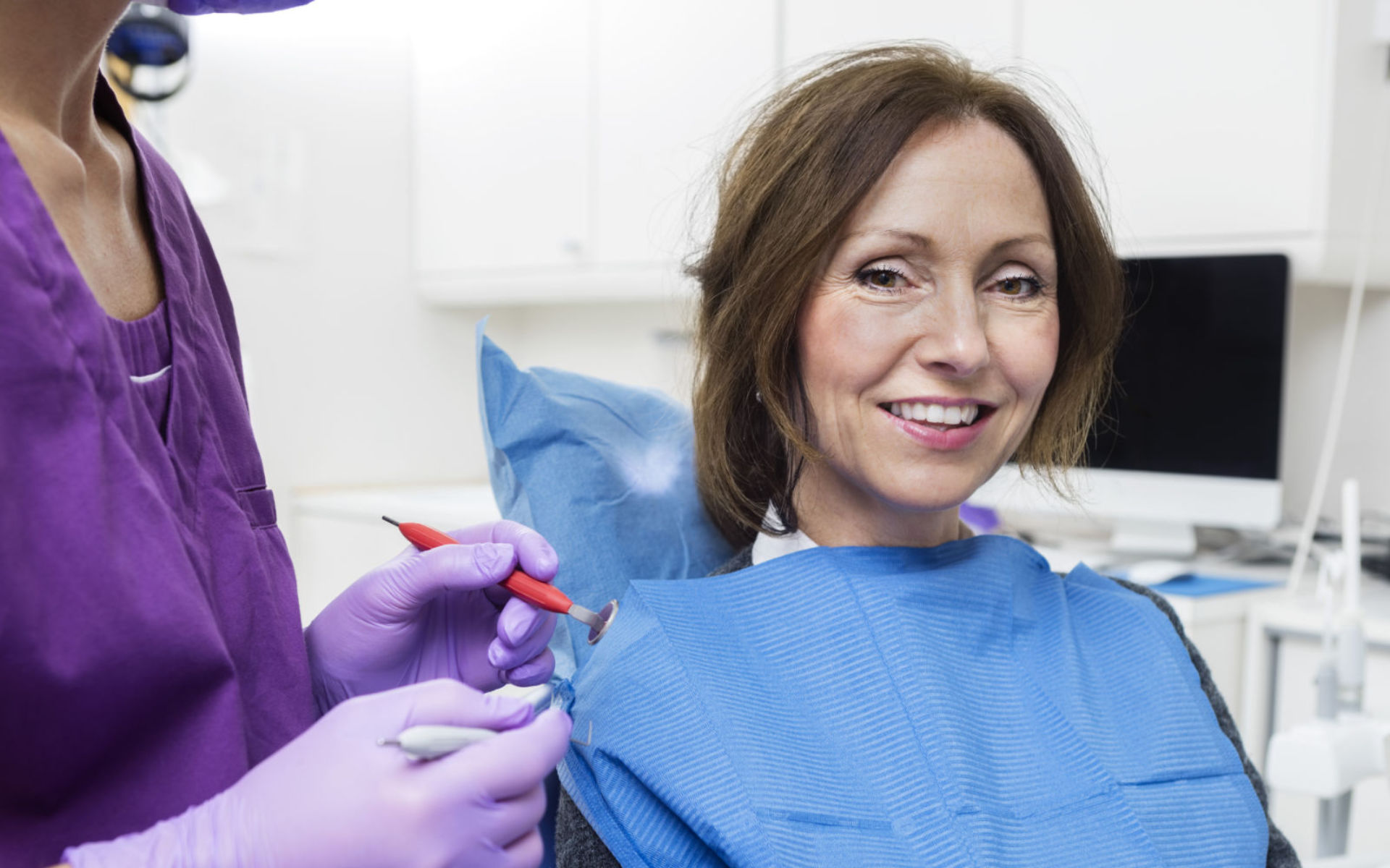 A relaxed smiling mature woman sitting in a dentist chair after dental treatment.