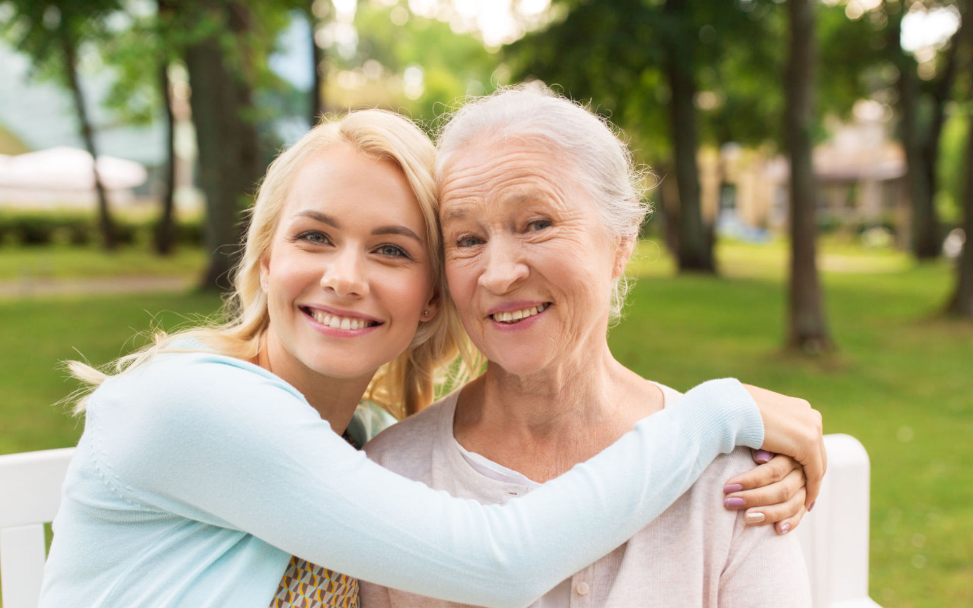 A smiling young woman embracing her happy grandmother.