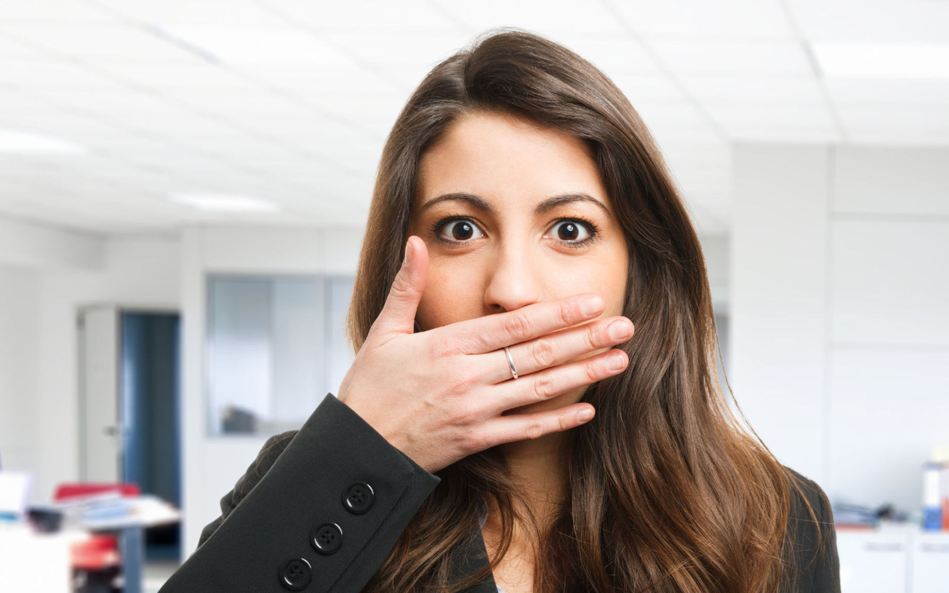 A concerned woman covering her mouth with a hand due to bad breath.