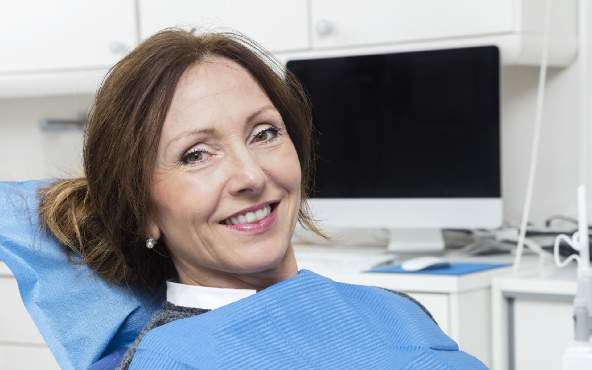 A relaxed smiling mature woman sitting in a dentist chair after dental treatment.