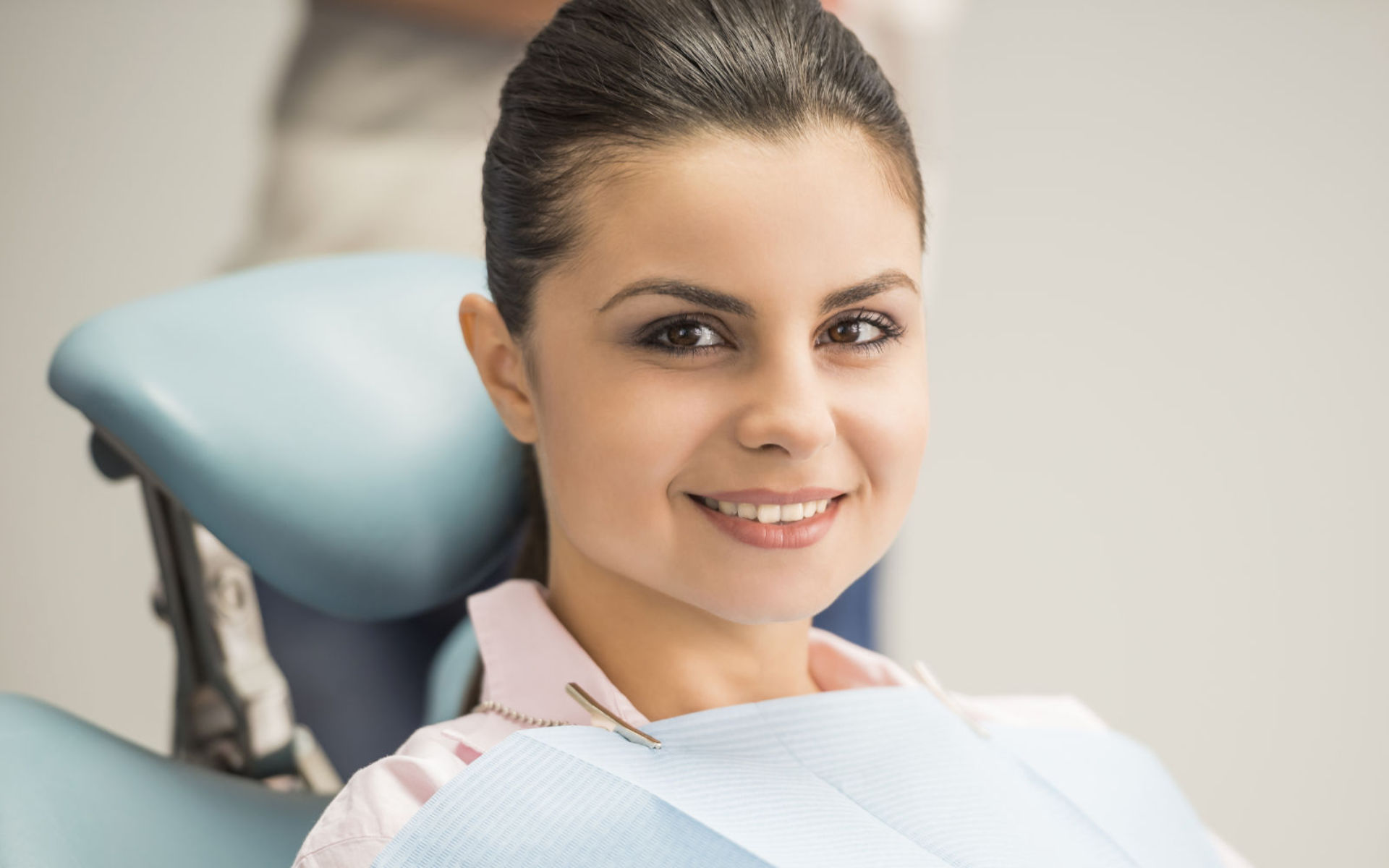 A satisfied young woman sitting in a dentist chair after dentla treatment.