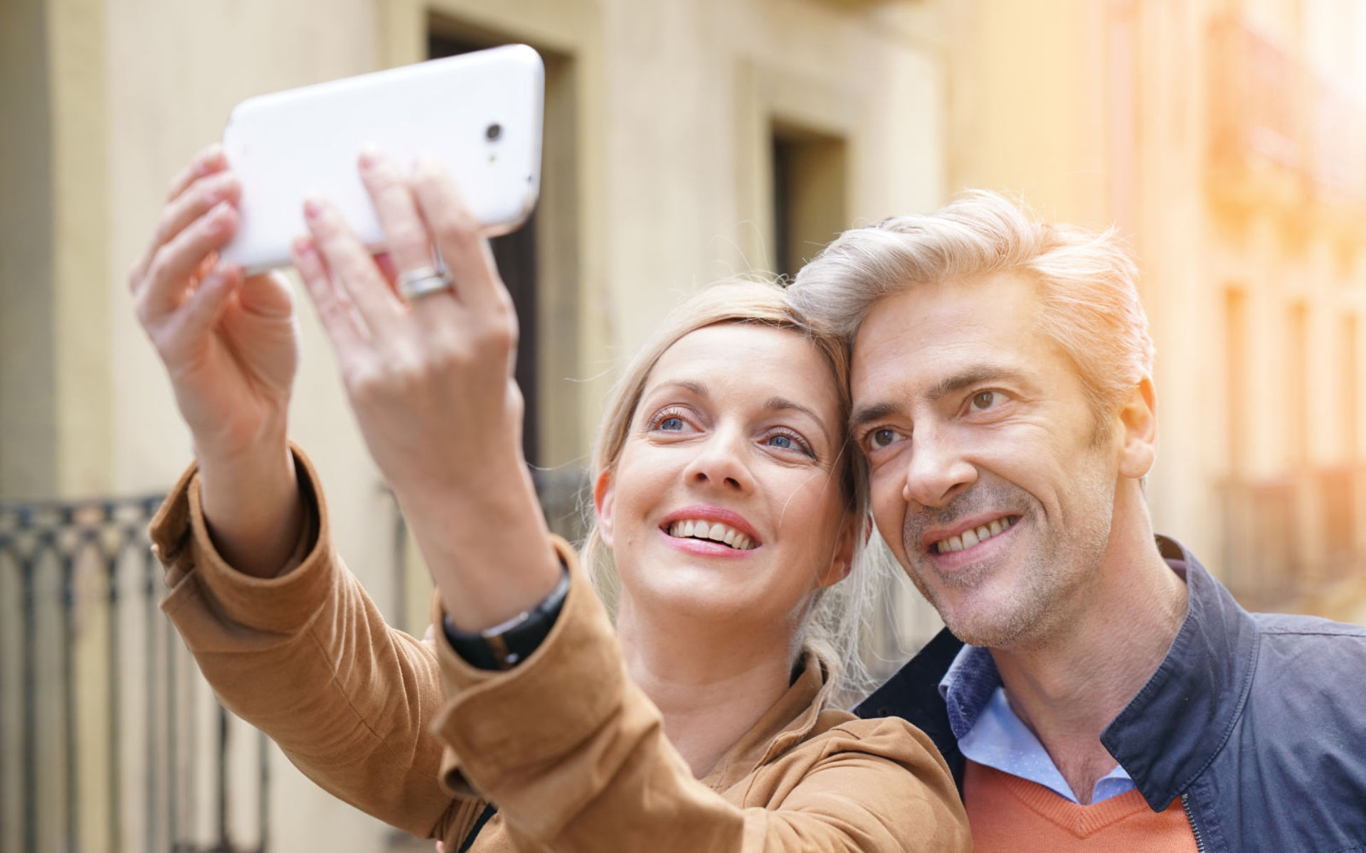 Smiling mature couple taking a selfie on a street.