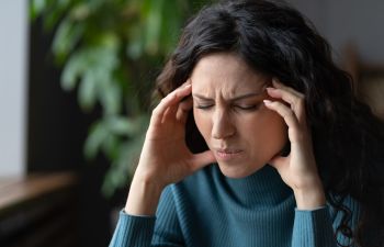 Woman suffering from headache caused by TMJ syndrome.