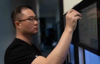 Dental laboratory technician operating a device.