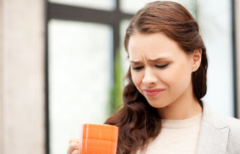 woman with orange mug demonstrates disgust twisting face