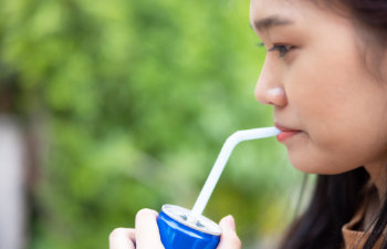 girl drinking a drink through a straw from a can